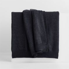 a black sweater folded on top of a white surface