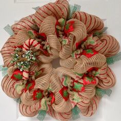 a burlock wreath with holly and candy canes on the front door for christmas