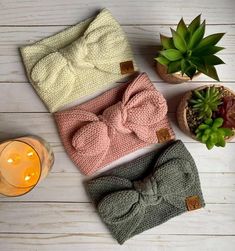 three knit headbands with bows on them next to a candle and succulent plant