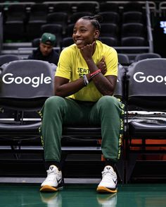 a man sitting on top of a bench in front of a basketball court with his hands crossed