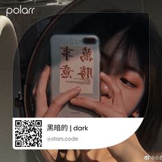 a woman looking at her cell phone in front of a mirror with chinese characters on it