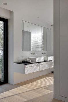 a bathroom with two sinks, mirrors and large sliding glass doors leading to the outside