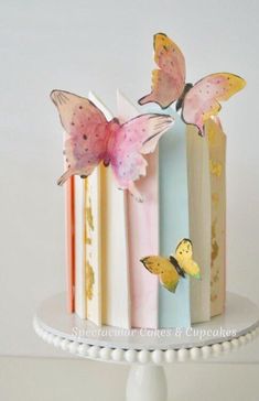 there is a cake decorated with butterflies on the top and bottom tier, as well as books