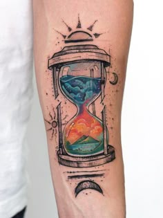 an hourglass tattoo on the arm with watercolors and sand in it,