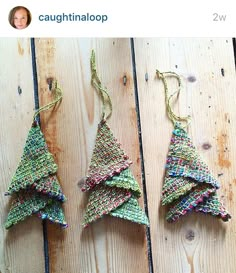 three small christmas trees made out of yarn sitting on top of a wooden table next to each other