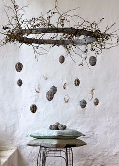 a table with a bunch of rocks hanging from it's side and some branches in the background