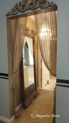 an ornate mirror in the middle of a hallway with curtains on it's sides