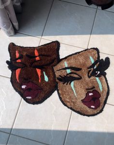 two rugs with faces painted on them sitting on the floor next to each other