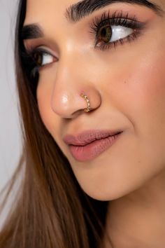 a close up of a woman with long hair and piercings on her nose looking at the camera