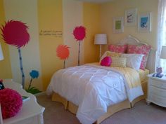 a bedroom decorated in yellow and pink with flowers painted on the wall behind the bed