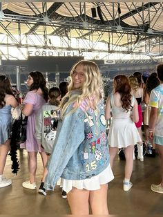 a woman standing in front of a group of people wearing short shorts and denim jackets