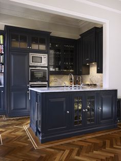 a kitchen with dark blue cabinets and wooden floors