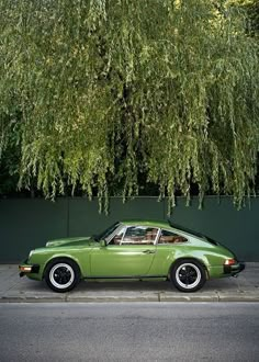 a green car parked next to a tree