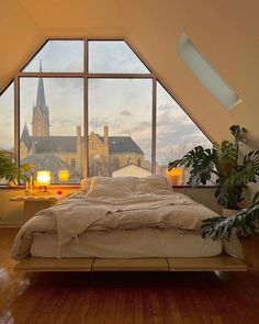 a bedroom with a large window and wooden flooring, along with a bed in the middle