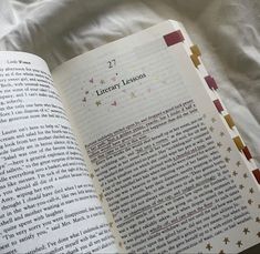 an open book sitting on top of a bed next to a white sheet with stars