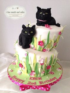 two cats sitting on top of a three tiered cake