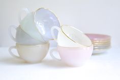 three cups with saucers stacked on top of each other in different colors and sizes