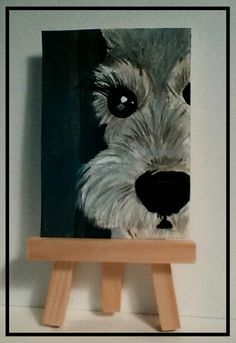 a small wooden easel with a painting of a dog's face on it