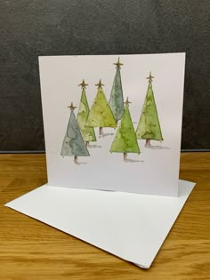 a card with watercolor christmas trees on it