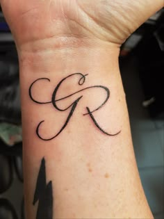 a person with a tattoo on their wrist that has the letter g and is in cursive writing