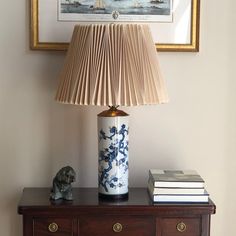 a lamp sitting on top of a wooden table next to a book and a vase