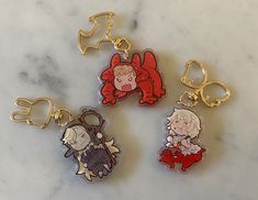 four keychains with cartoon characters on them sitting on a marble counter top,