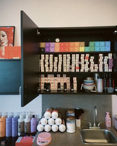 there are many different items on the shelf above the sink in this kitchen, including soaps and lotions