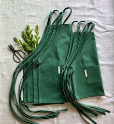 Multiple matching kids aprons in the color teal. Flat lay on white surface. Healing Crystals Decor, Banda Bags, Alpaca Wool Blanket, Matcha Tea Powder, Childrens Aprons, Black Honey, Ethical Shopping, Natural Textiles, Eco Chic