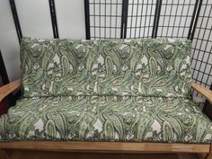 a green and white couch sitting on top of a wooden floor next to a wall