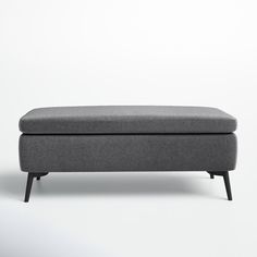 an upholstered bench with black legs and a gray cushion on the bottom, in front of a white background