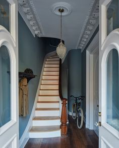 an entry way leading up to a set of stairs in a house with blue walls and wood flooring