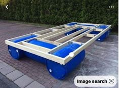 a large blue cart sitting on top of a brick road next to a green bush