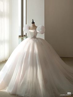 a white wedding dress on display in front of a window with the light coming through it