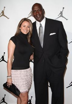 a man and woman standing next to each other in front of a wall with basketballs on it