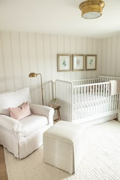 a baby's room with a white crib, chair and ottoman