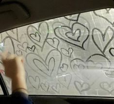 someone is drawing hearts on the windshield of a car