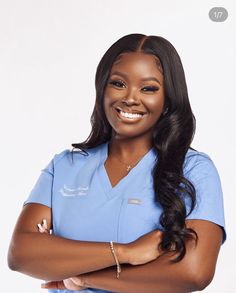 a smiling woman in scrubs with her arms crossed