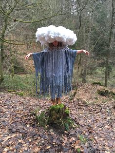 a scarecrow standing in the woods with his arms spread out and head covered by yarn