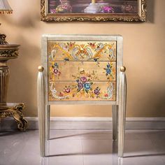 an ornately decorated chest of drawers in front of a painting on the wall and floor