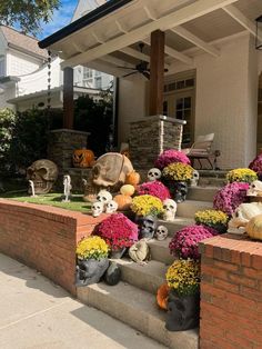 the front porch is decorated for halloween with fake pumpkins, flowers and skulls on it