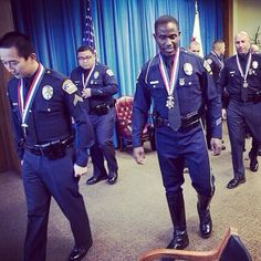 several police officers are walking around with medals on their necks and chests, in front of a blue curtain