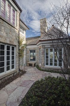 a stone building with two windows and a brick walkway leading to the front door area