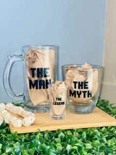 two mugs sitting on top of a wooden board next to marshmallows