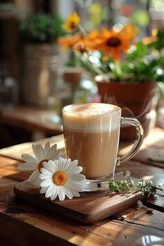 a cup of coffee sitting on top of a wooden table next to a flower pot