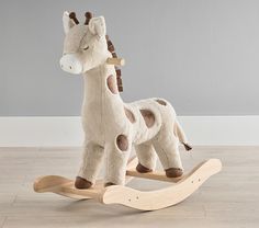 a stuffed giraffe sitting on top of a wooden rocking horse with long legs