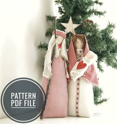 two cloth dolls are standing next to each other in front of a small christmas tree