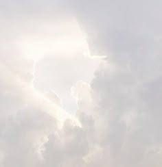 an airplane is flying through the cloudy sky