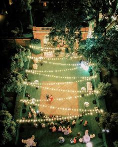 an aerial view of people sitting on the lawn at night with string lights strung around them