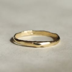 a yellow gold wedding band on top of a white surface with no other ring in the middle