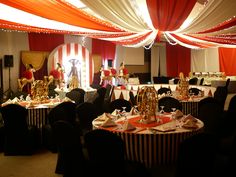 a banquet room set up with red and white striped tablecloths, black chairs, and gold decorations